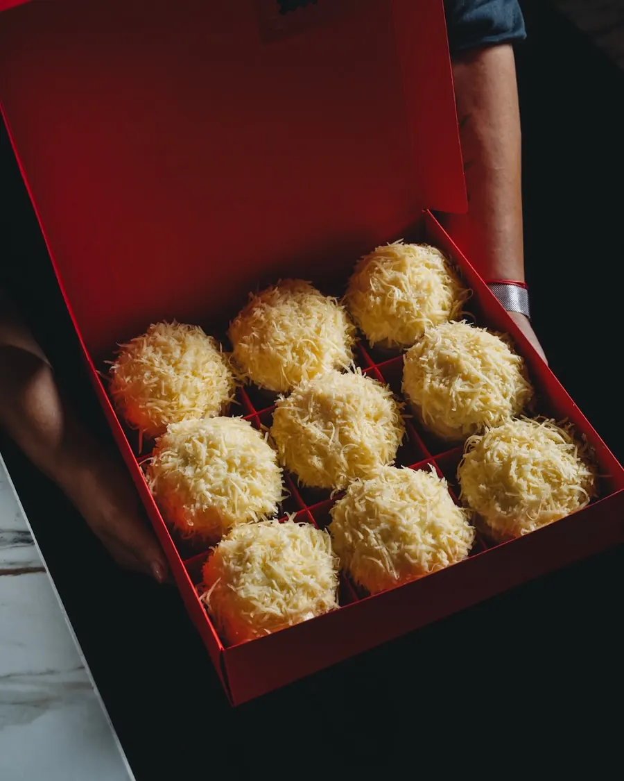 An open SHUKR box with a cheese-topped ensaymada