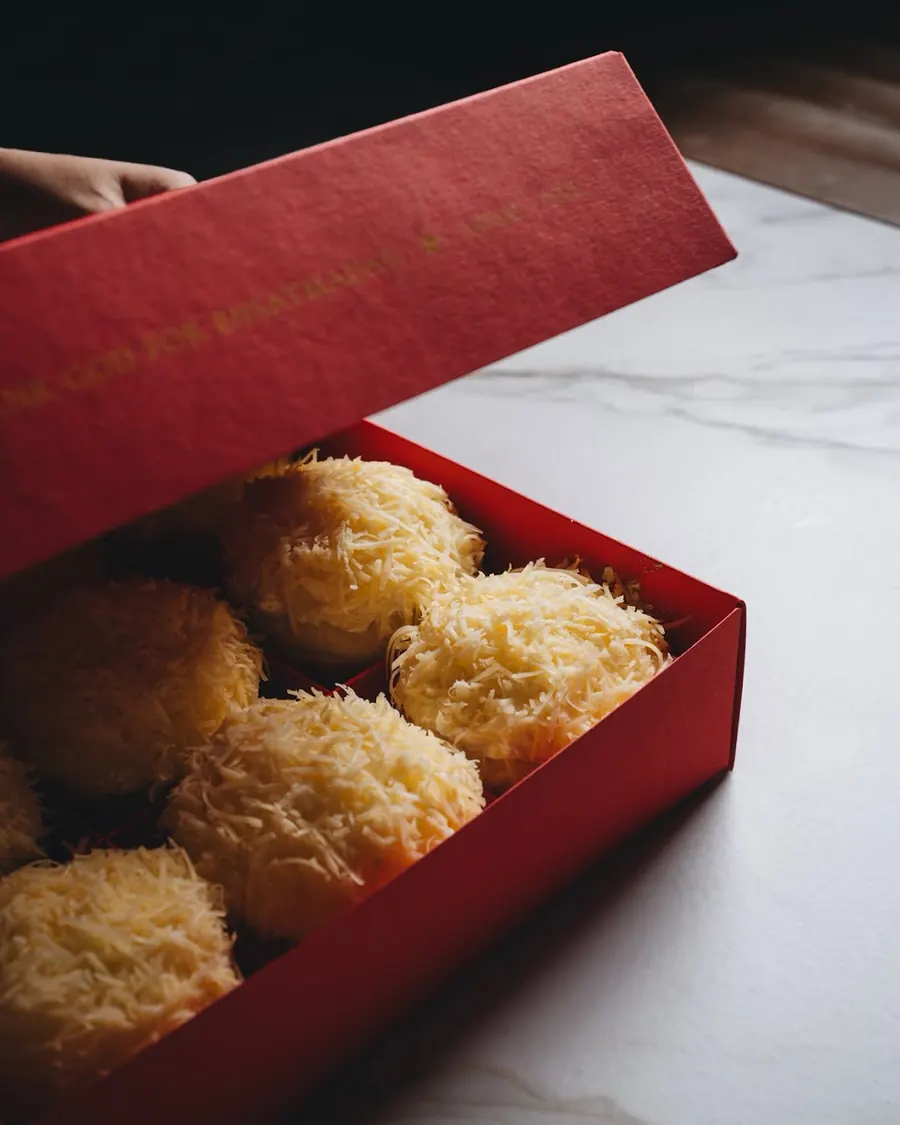 A SHUKR ensaymada in its box on a marble counter