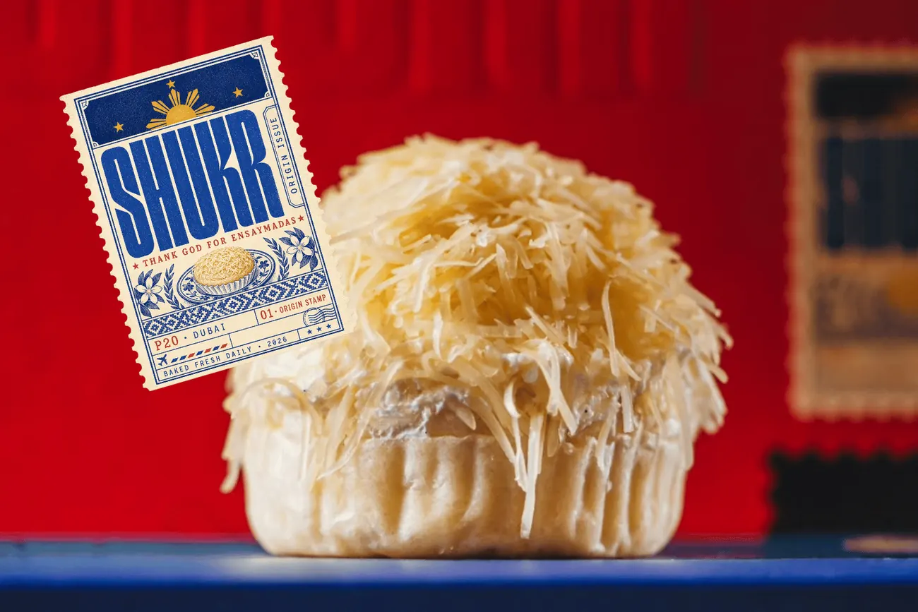 A SHUKR ensaymada topped with grated cheese, beside the SHUKR stamp artwork